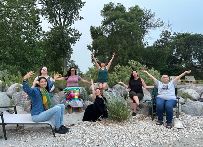 Group of people sitting on rocks by the water.
