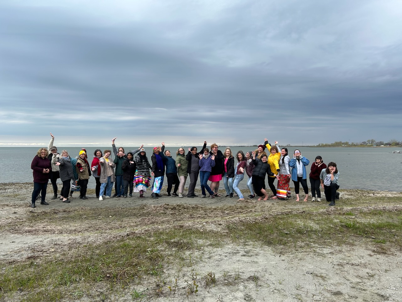 Group of people standing on the shore by a lake.