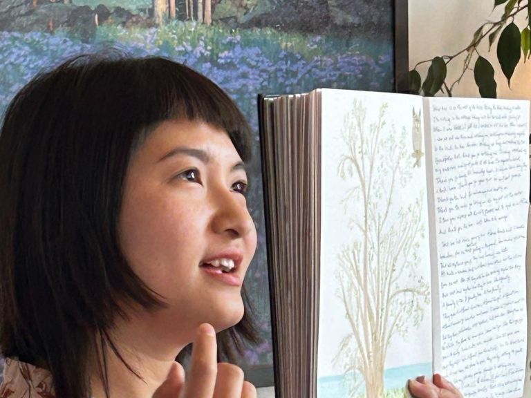 Person holding up book with drawing on one page and words on the other.