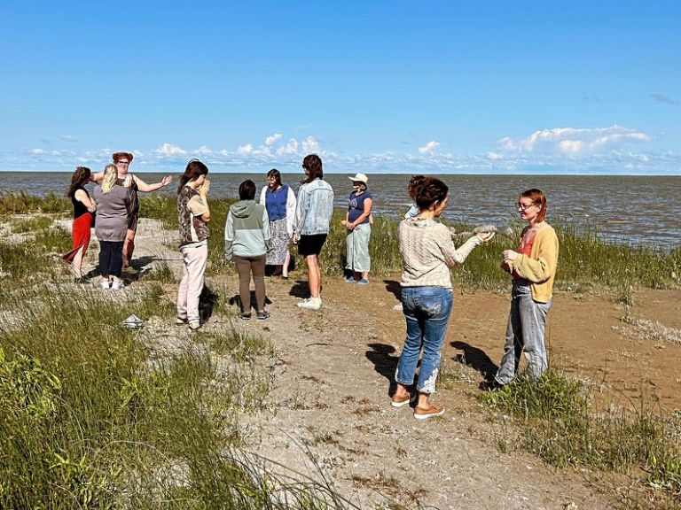 Group of people standing along shoreline.
