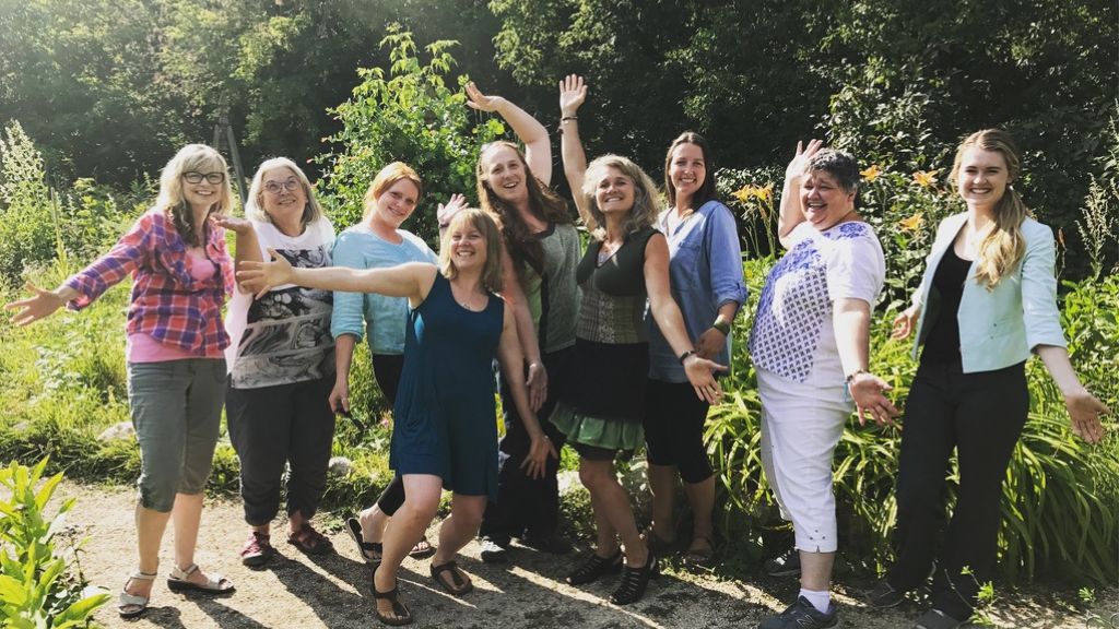 Group of people standing together in front of trees.