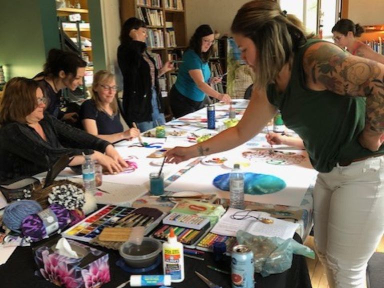 Group of people working on paintings on table.