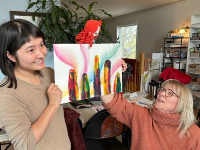 Two people holding up painting.