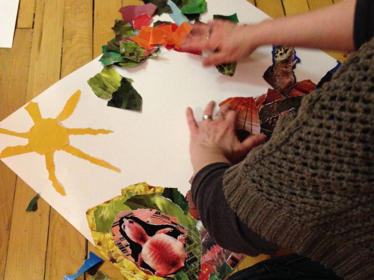 Person sitting on floor working on collage.