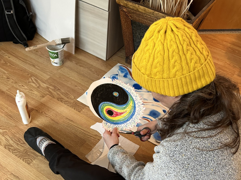 Person sitting on the floor working on an art project.