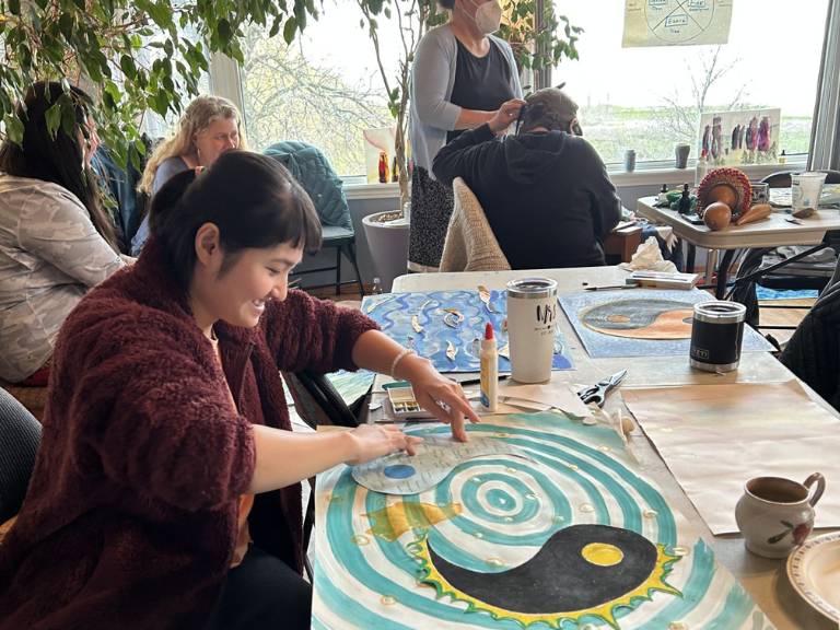 Person sitting down at a table working on an art project.