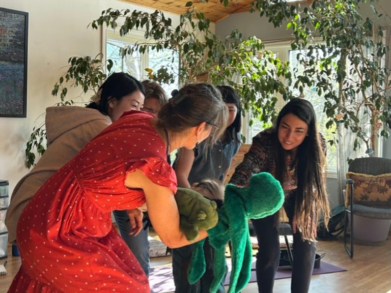 Group of people standing and using two puppets.