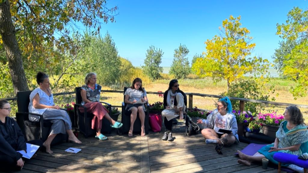 Group of people sitting on a deck with trees in the background.