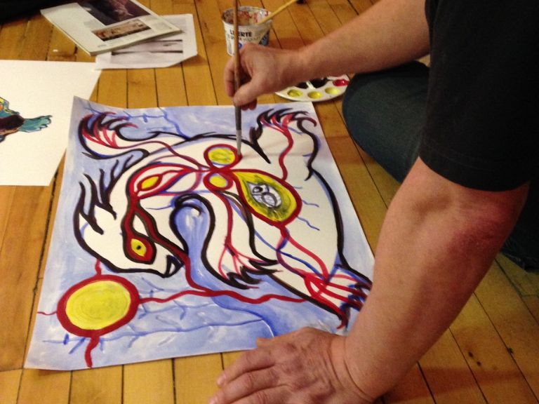 Person sitting on floor working on painting.