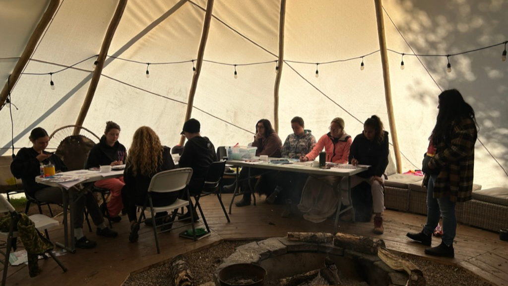 Group of people working at folding tables in tipi.