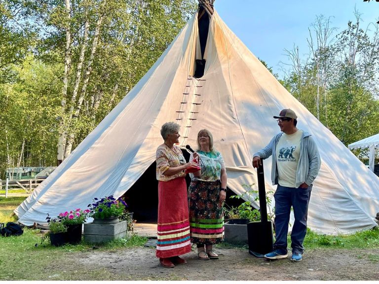 Group of people standing in front of tipi.