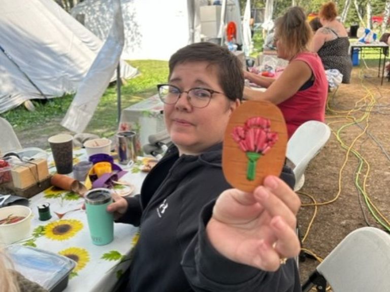 Person sitting at table holding up floral design.