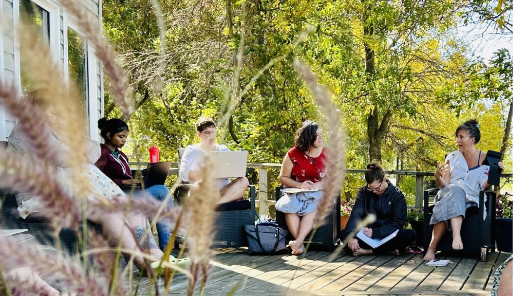Group of people sitting on chairs on a deck.
