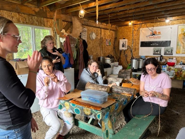 Group of people sitting in a garage at apicnic table.