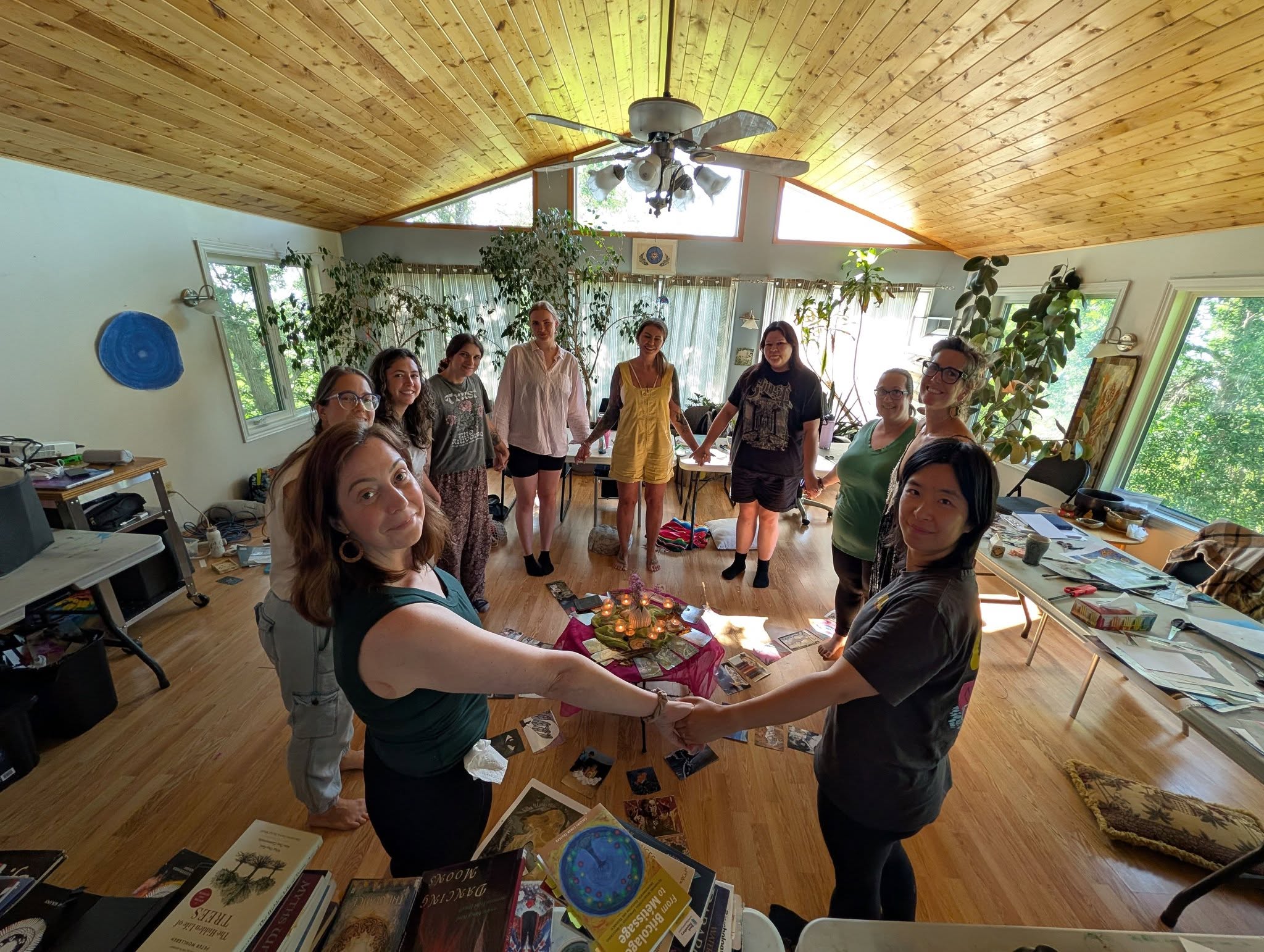Group of students holding hands in a circle, standing around art installation centred on ground in Painted Sky Studio space